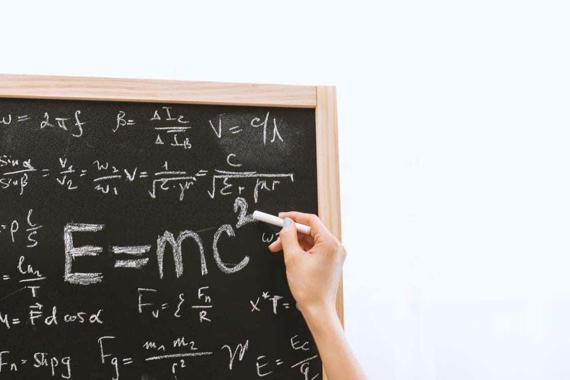 A person writing math formulae on a blackboard