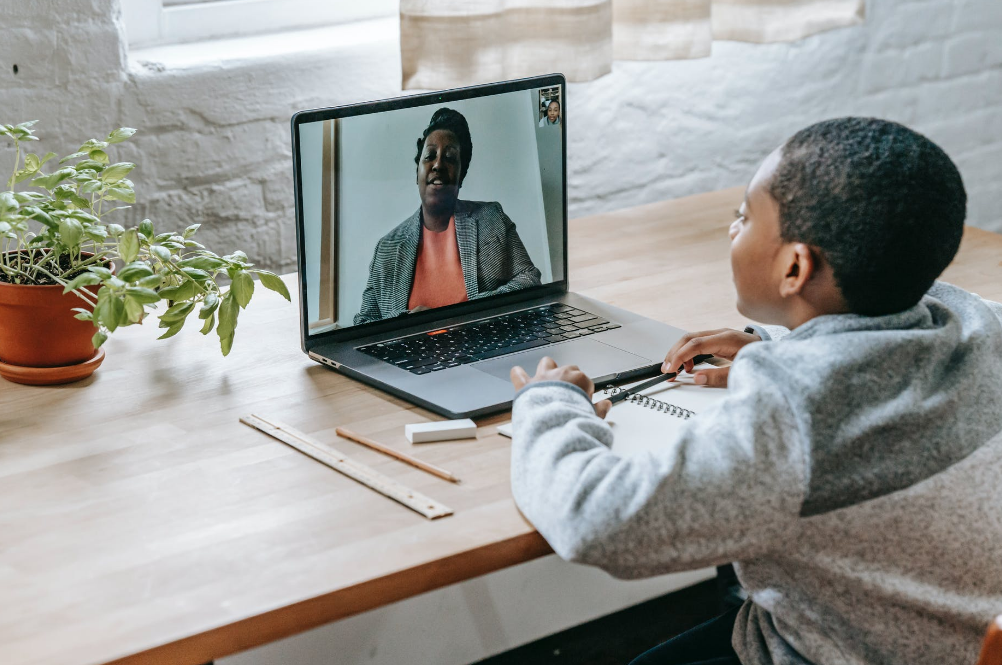 A boy is talking to his teacher in a virtual class for kids
