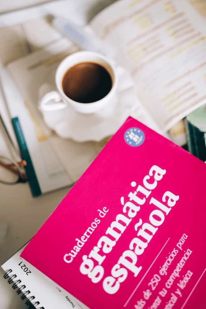 A Spanish grammar textbook next to a cup of coffee