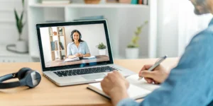 Student on a laptop taking notes during an online class for distance learning in the pandemic.