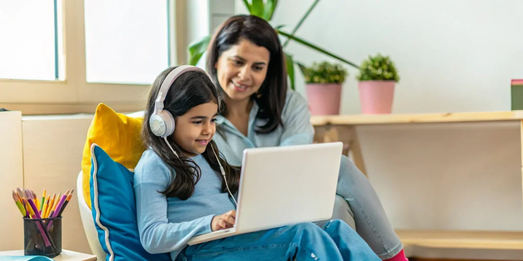 Student struggling with an online class on a laptop while a parent offers help.