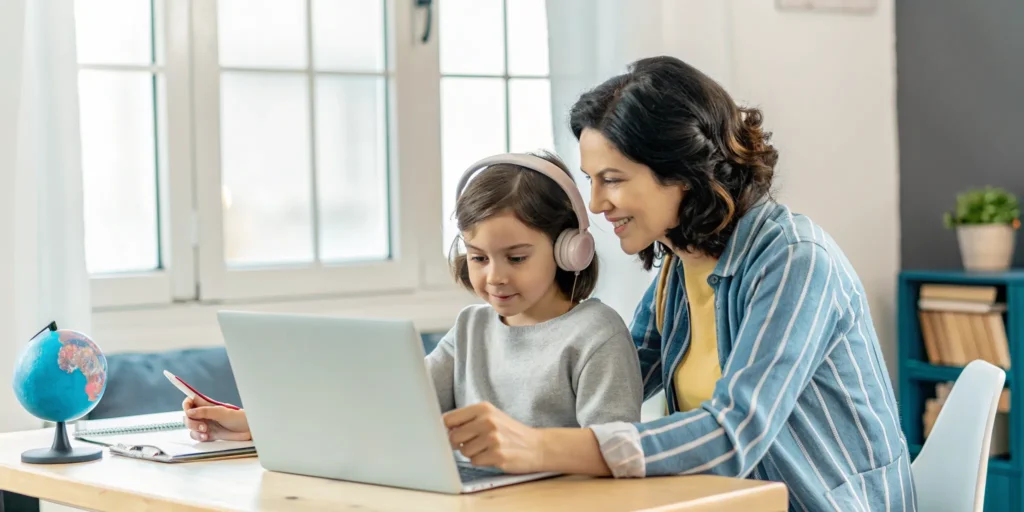 Parent and child using a laptop for a bilingual online homeschool program in NH.
