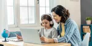 Parent and child using a laptop for a bilingual online homeschool program in NH.