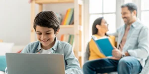 Student learning on laptop with parent nearby in a bright home learning space