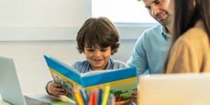 Student reading a Spanish storybook at a bright home desk with a parent nearby
