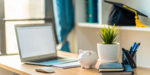Piggy bank and graduation cap on a desk for an accredited online school under $6,000 per year.