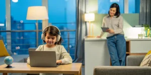 Expat child attending an affordable private online school on a laptop with a parent nearby.